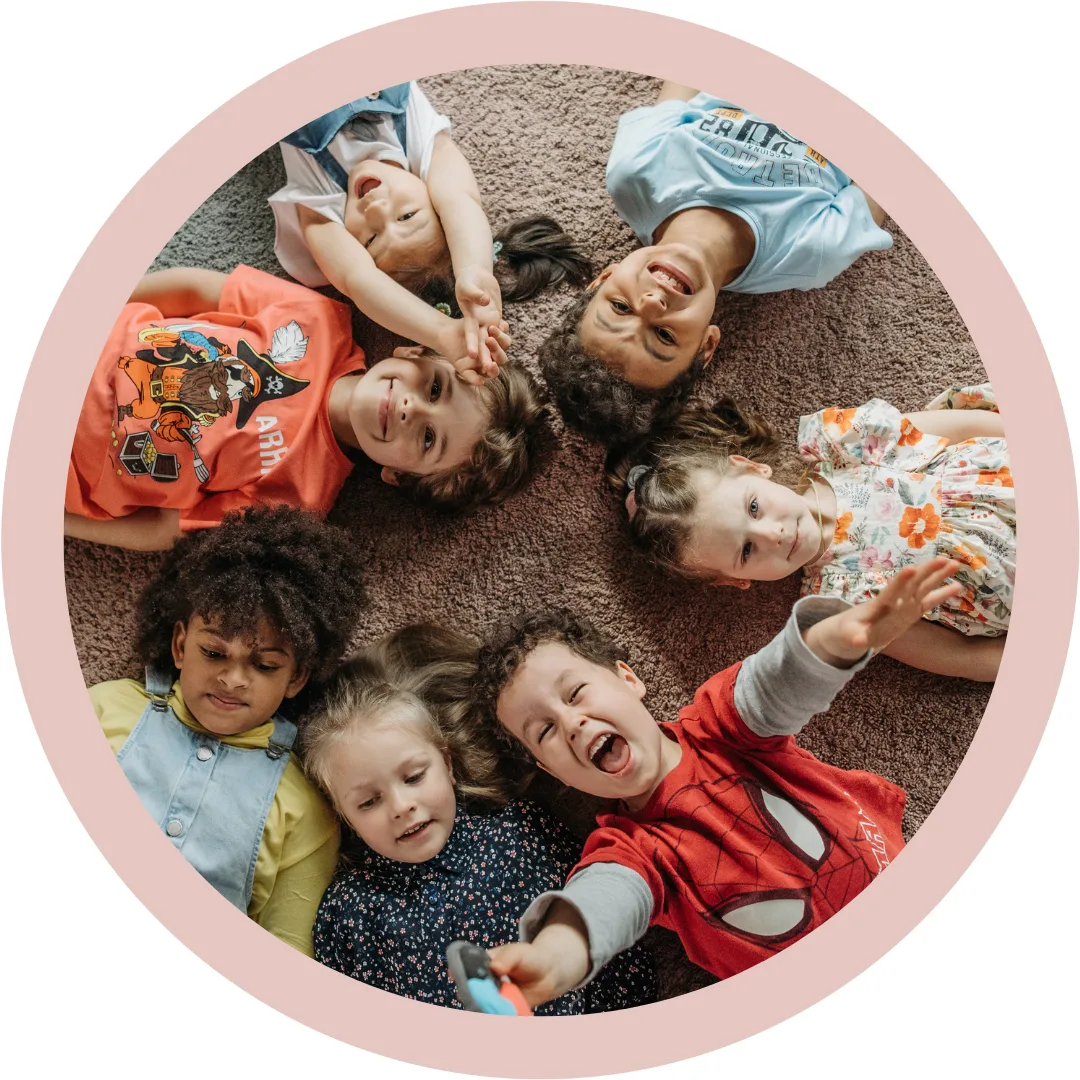 Kinder liegen im Kreis auf dem Boden und lachen – gemeinsames Lernen mit Freude